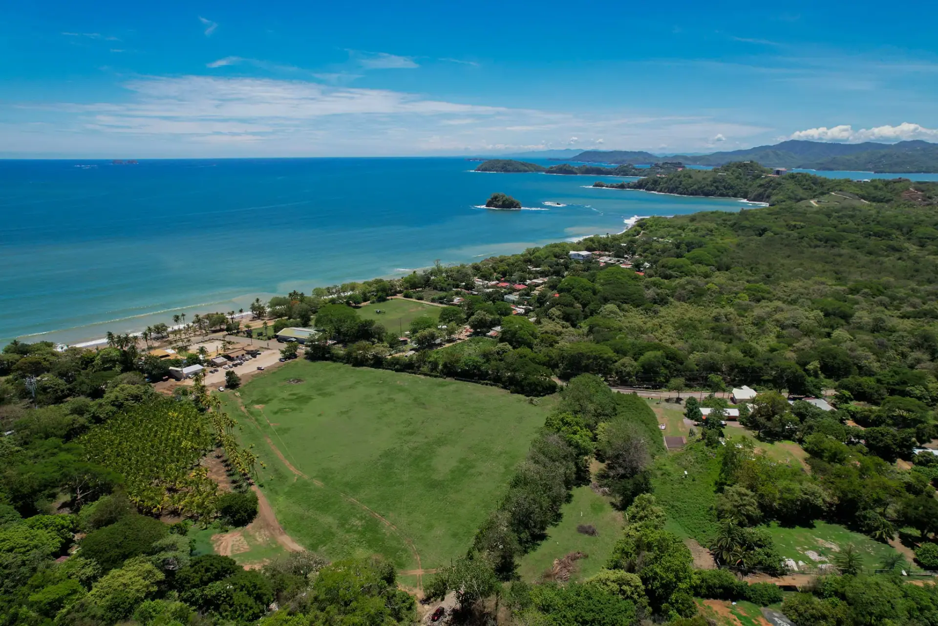Aerial view of green oceanfront land parcels meeting the sea