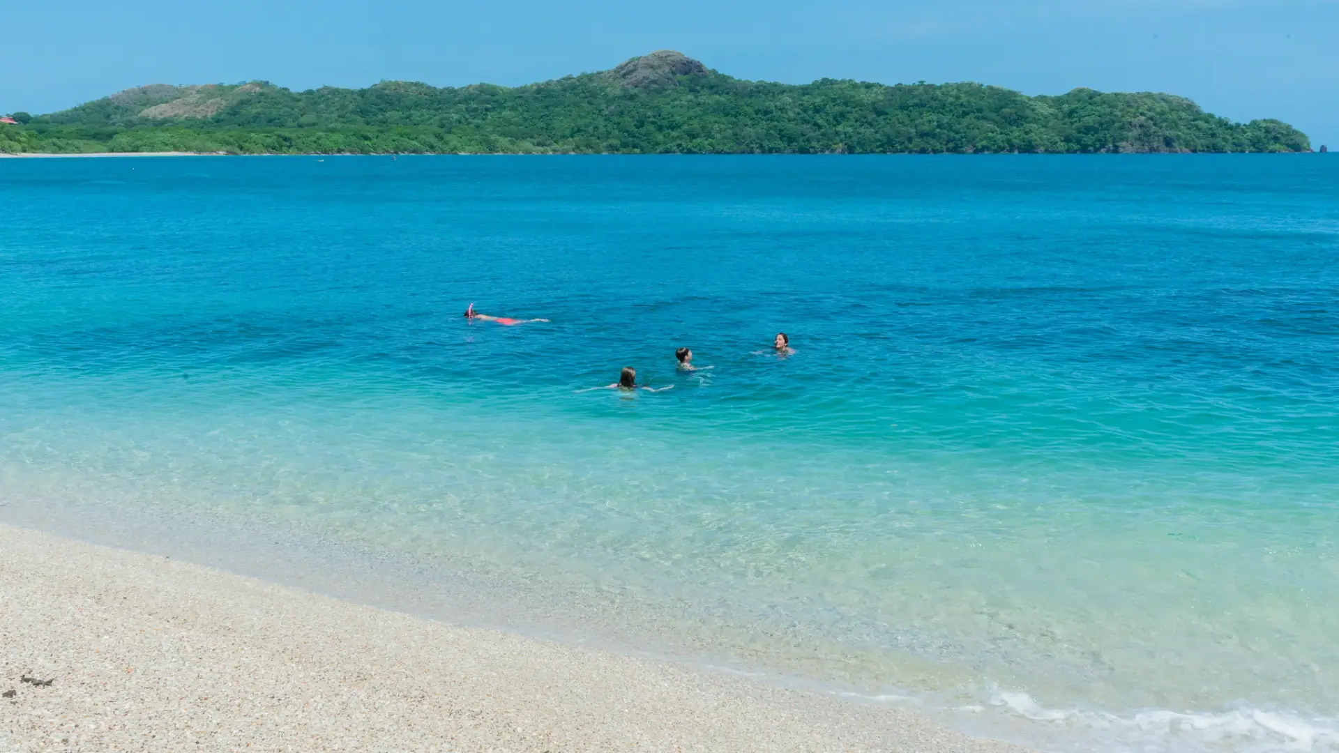 Swimmers in the turquoise shallows of Playa Conchal